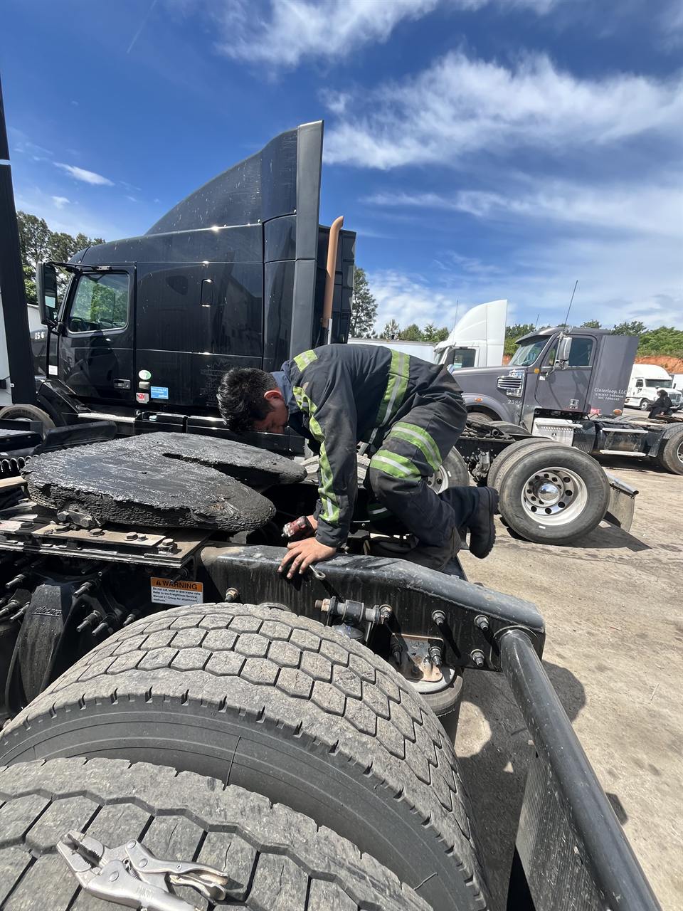 Technician servicing a tractor-trailer fifth wheel and frame